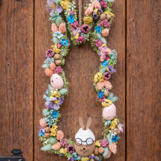 Veľkonočný veniec na dvere s vajíčkami, farebnými kvietkami a zajačikom s okuliarmi