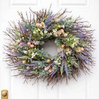 Jarný prírodný veniec na dvere z konárikov s eukalyptom, levanduľou a jemnými pastelovými kvetmi na bielych vchodových dverách.